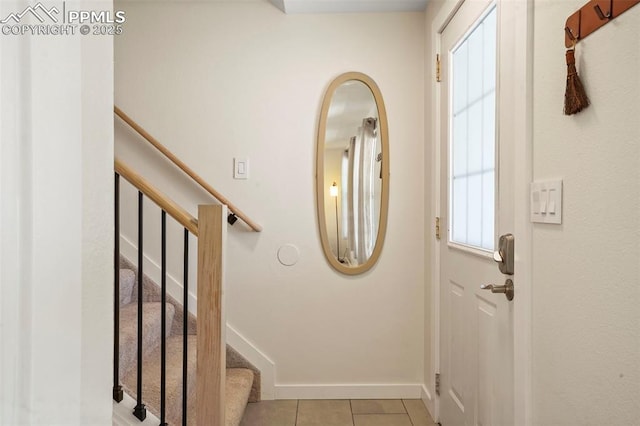 doorway to outside featuring light tile patterned floors, baseboards, and stairs