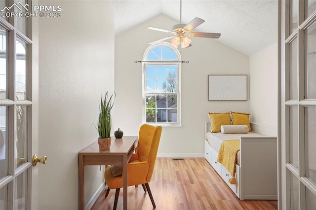 office space with a ceiling fan, a textured ceiling, vaulted ceiling, baseboards, and light wood-style flooring