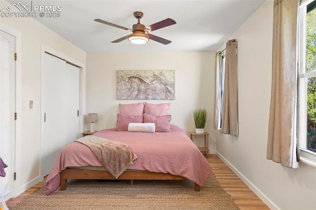 bedroom with baseboards, a ceiling fan, light wood-style flooring, and a closet