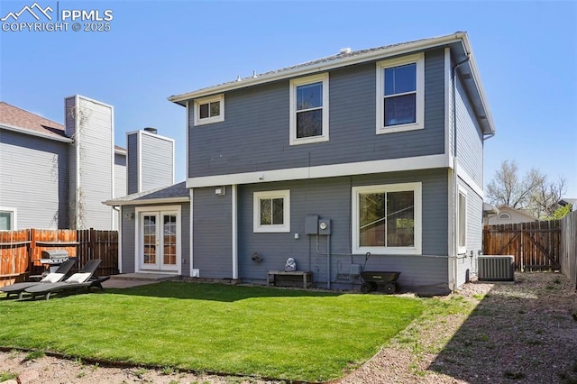 back of property featuring a lawn, a fenced backyard, central AC, and french doors
