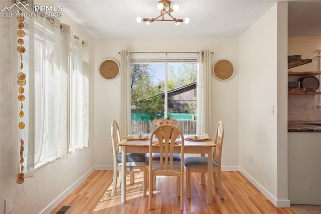 dining area featuring baseboards, a notable chandelier, and light wood-style floors