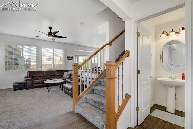 staircase featuring a ceiling fan, baseboards, and wood finished floors