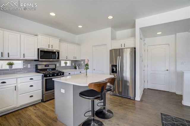 kitchen featuring dark wood-style floors, a center island, white cabinetry, tasteful backsplash, and appliances with stainless steel finishes