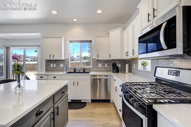 kitchen with light countertops, white cabinets, appliances with stainless steel finishes, and a sink