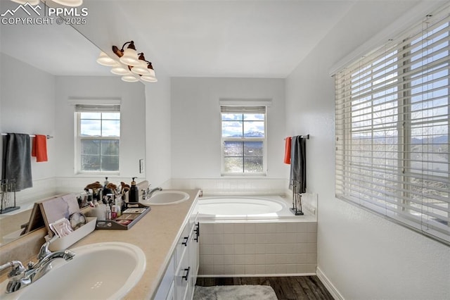 full bathroom featuring double vanity, a sink, a bath, and wood finished floors