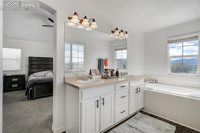 ensuite bathroom featuring a sink, a bath, ensuite bath, and double vanity