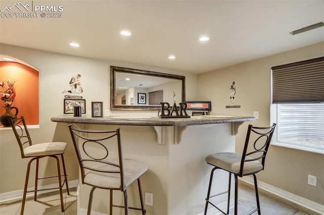 bar with bar, baseboards, and recessed lighting