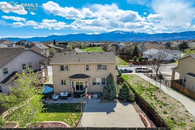 back of house with a fenced backyard, a residential view, a mountain view, and a patio area