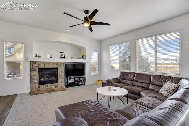 living room with a ceiling fan, baseboards, plenty of natural light, and a stone fireplace