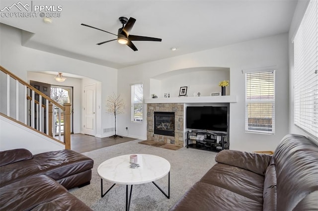 carpeted living area featuring ceiling fan, a wealth of natural light, and stairway