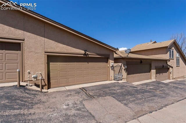 6151 Pine Hill Dr, Colorado Springs, CO 80918 - exterior space with community garages, a gate, and stucco siding