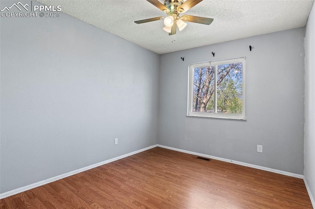 empty room featuring ceiling fan, a textured ceiling, visible vents, and wood finished floors