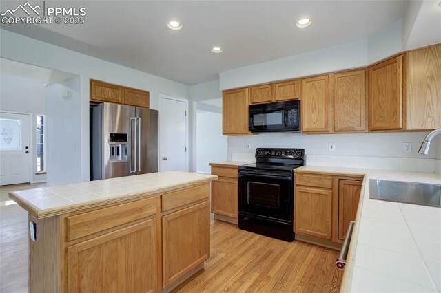 7884 Gladwater Rd, Peyton, CO 80831 - kitchen with tile counters, recessed lighting, a sink, light wood finished floors, and black appliances