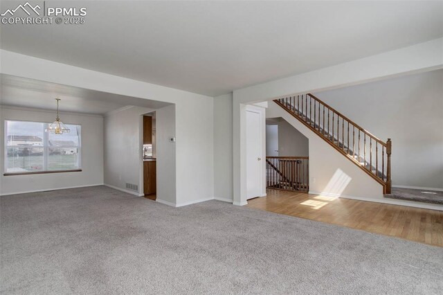 7884 Gladwater Rd, Peyton, CO 80831 - unfurnished living room featuring baseboards, carpet flooring, a chandelier, and stairway