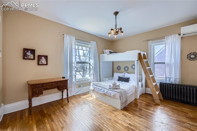 bedroom featuring a notable chandelier, hardwood / wood-style floors, baseboards, and radiator heating unit