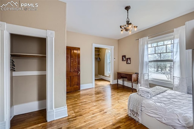 bedroom featuring a chandelier, a closet, baseboards, and wood finished floors