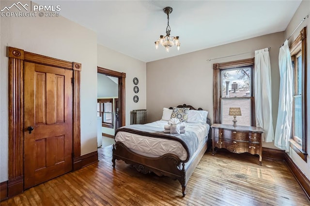 bedroom featuring an inviting chandelier, hardwood / wood-style flooring, baseboards, and multiple windows