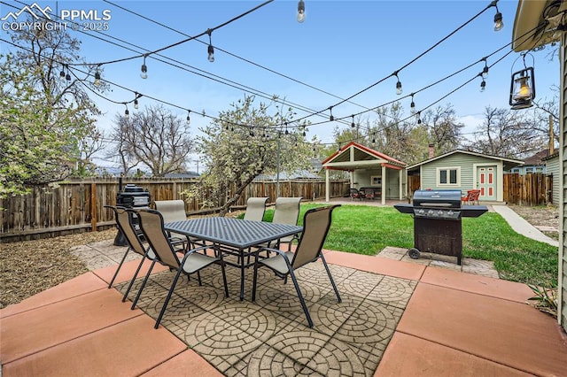 view of patio / terrace featuring outdoor dining area, an outbuilding, a fenced backyard, and grilling area