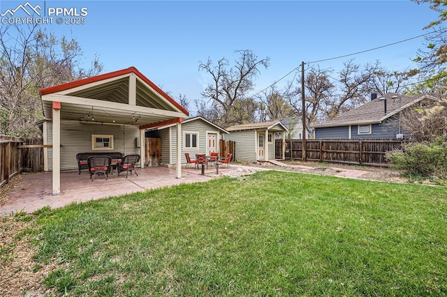 rear view of property with a yard, a patio, an outdoor structure, and a fenced backyard