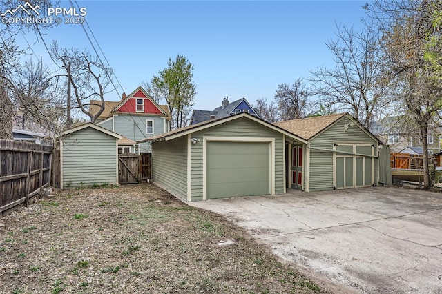 exterior space with concrete driveway, an outdoor structure, and fence