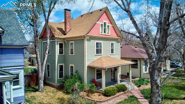rear view of house featuring a chimney, a shingled roof, covered porch, and fence