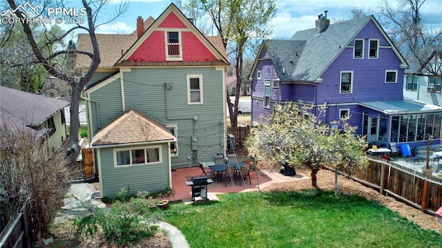 back of house with a fenced backyard, a patio, a chimney, and a lawn