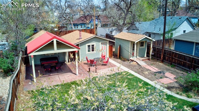 rear view of property with an outbuilding, a jacuzzi, a patio area, a fenced backyard, and a storage unit