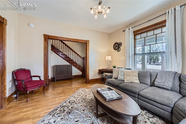living room featuring light wood-type flooring, baseboards, stairs, and radiator heating unit