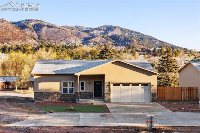 ranch-style home with stone siding, stucco siding, a mountain view, and fence