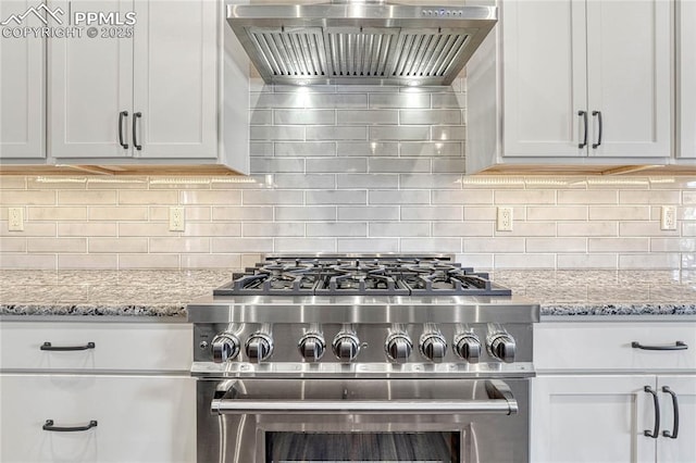 kitchen with white cabinets, wall chimney exhaust hood, stainless steel stove, and backsplash