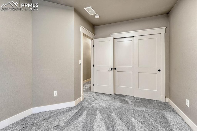 unfurnished bedroom with carpet flooring, baseboards, a closet, and visible vents