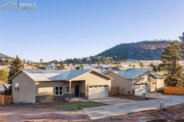 single story home featuring stone siding, a mountain view, and fence