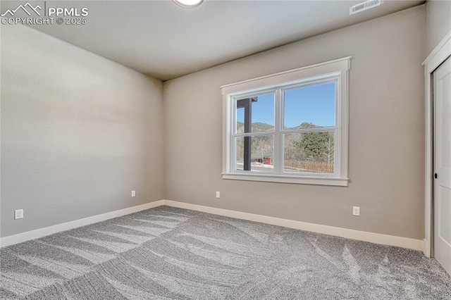 carpeted spare room featuring visible vents and baseboards