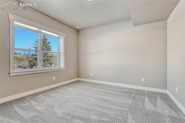 carpeted spare room featuring baseboards