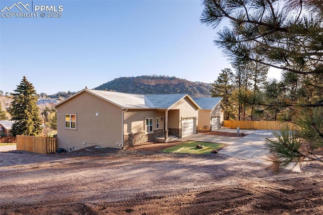 view of front facade featuring fence, an attached garage, stucco siding, and driveway