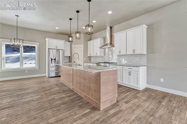 kitchen with wall chimney exhaust hood, stainless steel fridge, decorative backsplash, and light wood-type flooring