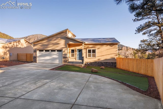 view of front of property with fence, stucco siding, stone siding, and concrete driveway