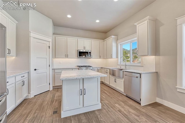 kitchen with a sink, white cabinetry, light wood-style floors, tasteful backsplash, and appliances with stainless steel finishes