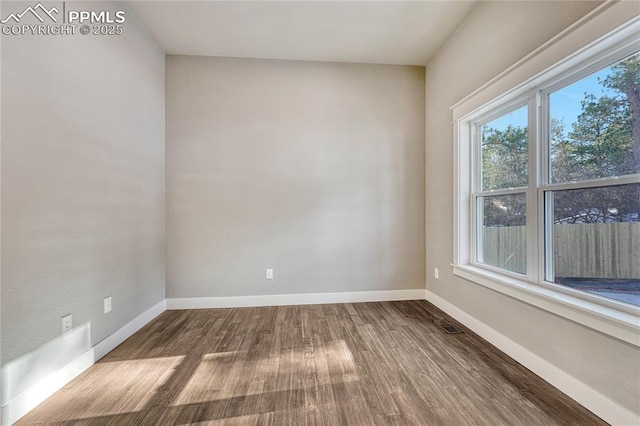 spare room featuring baseboards and wood finished floors