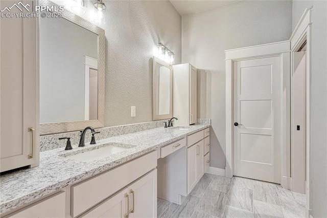 bathroom with a sink, double vanity, and a textured wall