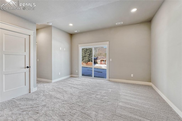 spare room with baseboards, visible vents, and carpet