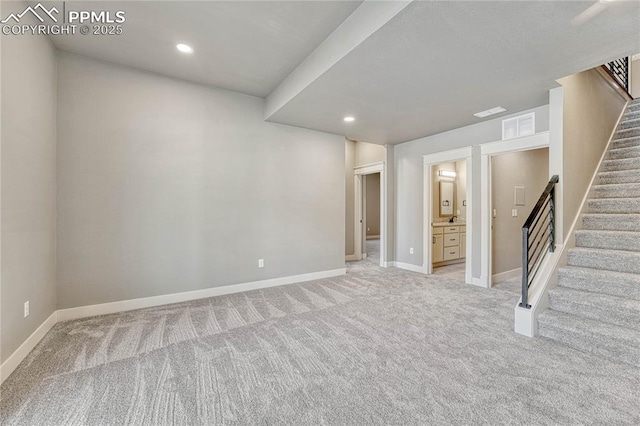 basement featuring light colored carpet, stairs, and baseboards