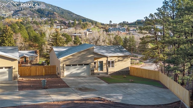 view of front of house featuring a mountain view, stucco siding, driveway, and fence