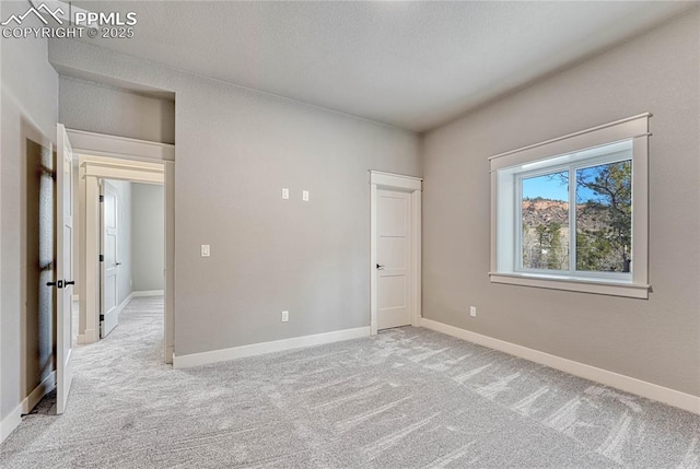 unfurnished room with baseboards and light colored carpet