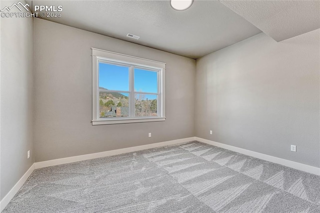 empty room with a textured ceiling, visible vents, baseboards, and carpet floors