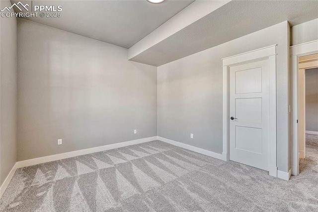 carpeted spare room featuring baseboards