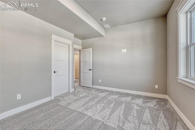 empty room with plenty of natural light, baseboards, and carpet floors
