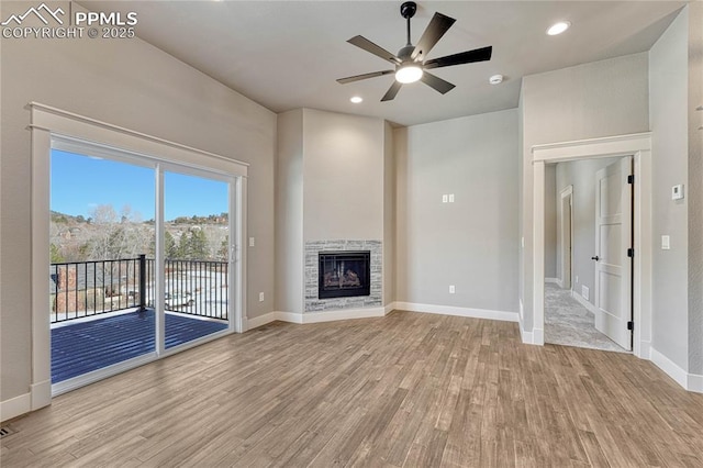 unfurnished living room featuring light wood-type flooring, baseboards, a stone fireplace, ceiling fan, and recessed lighting