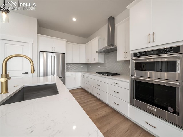 3188 Virga Loop, Colorado Springs, CO 80904 - kitchen with a sink, white cabinetry, decorative backsplash, wall chimney exhaust hood, and appliances with stainless steel finishes
