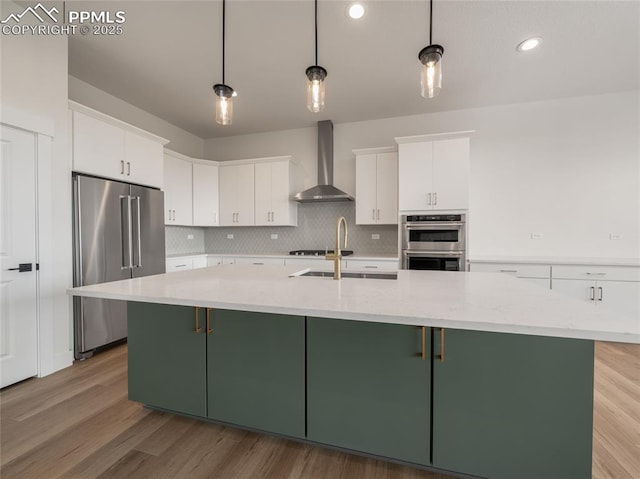3188 Virga Loop, Colorado Springs, CO 80904 - kitchen featuring a sink, stainless steel appliances, white cabinetry, green cabinets, and wall chimney range hood